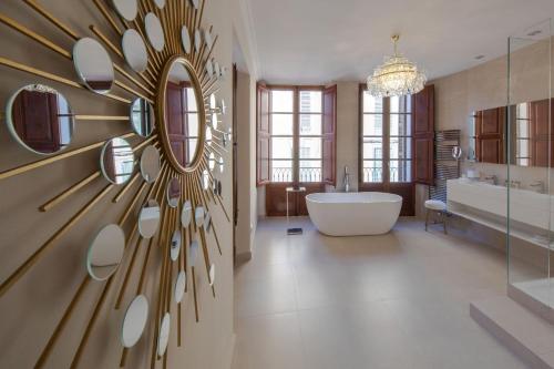 uma casa de banho com uma banheira e um espelho grande em Palacio Can Marqués em Palma de Maiorca