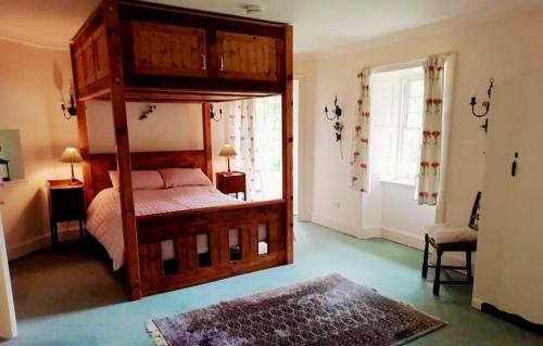 1 dormitorio con cama con dosel y ventana en Forget Me Not Holiday Cottage en Dalmellington