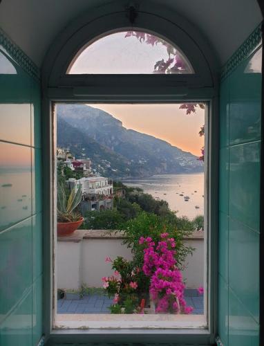 a window with a view of the ocean and flowers at Hotel Dimora Fornillo in Positano