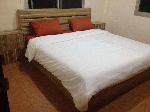 a large bed with white sheets and orange pillows at Janson's House in Ban Mae Kon