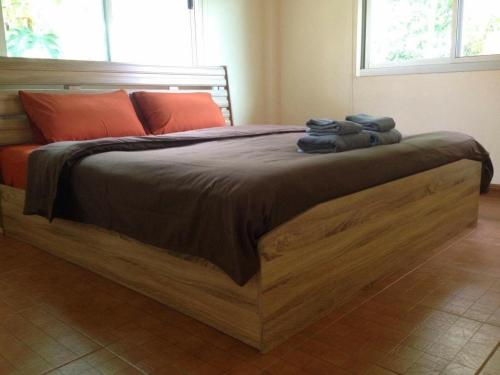 1 dormitorio con 1 cama grande de madera y toallas. en Janson's House en Ban Mae Kon