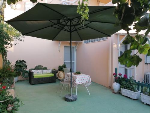 a green umbrella on a patio with a table at Trizinia View in Galatas