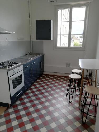 une cuisine avec des placards bleus, une cuisinière et des tabourets dans l'établissement Appartement 1-6 pers situé entre les ponts, à Saumur