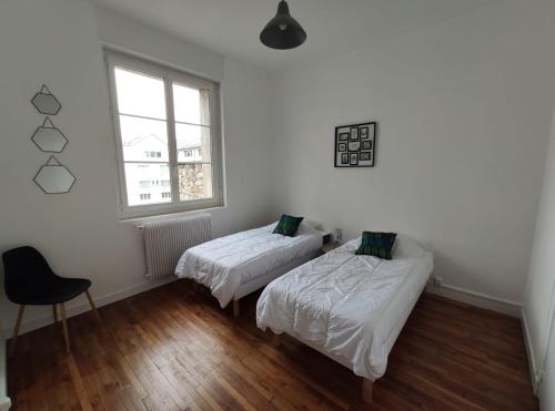 a room with two beds and a chair in it at Appartement 1-6 pers situé entre les ponts in Saumur
