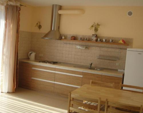 a kitchen with wooden cabinets and a table and a stove at Klaipedarent in Klaipėda