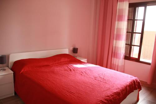 un lit rouge dans une chambre avec une fenêtre dans l'établissement Apartamento Katrina Balcón del mar, à Costa del Silencio