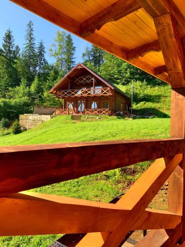 a wooden fence with a log cabin in the background at Терношорська Лада in Snidavka