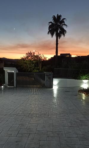 a patio with a fence and a palm tree at sunset at La Dimora Degli Artisti in Catanzaro