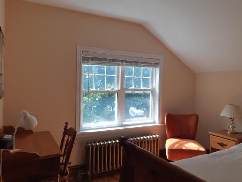 1 dormitorio con cama, ventana y silla en Comfy Stay - Close to Everything en Halifax