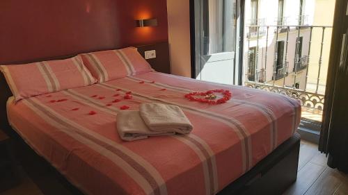 Una cama con flores rojas en ella con una ventana en Hostal Corazón de Madrid, en Madrid