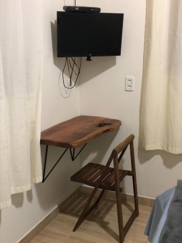 a wooden table with a chair and a television on a wall at Casa de São Jorge in Pirenópolis