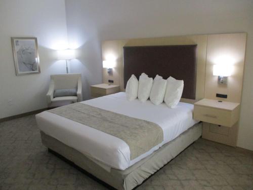 チッカシェーにあるBest Western Plus Chickasha Innの大きなベッドと椅子が備わるホテルルームです。