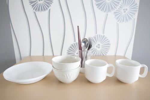 four white cups and plates on a table at SUMIYOSHI APARTMENT Hotel 住吉アパートメントホテル in Fukuoka