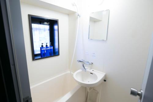 a white bathroom with a sink and a bath tub at SUMIYOSHI APARTMENT Hotel 住吉アパートメントホテル in Fukuoka