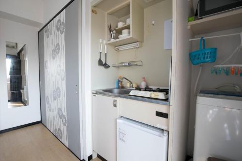 a small kitchen with a sink and a refrigerator at SUMIYOSHI APARTMENT Hotel 住吉アパートメントホテル in Fukuoka