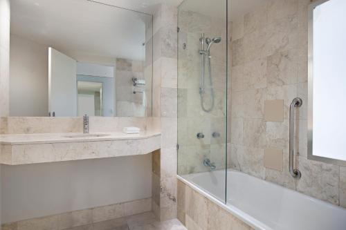 a bathroom with a shower and a tub and a sink at Mantra on View Hotel in Gold Coast