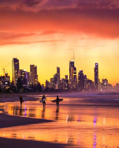 three people walking on the beach with their surfboards at Nobby Beach Holiday Village in Gold Coast
