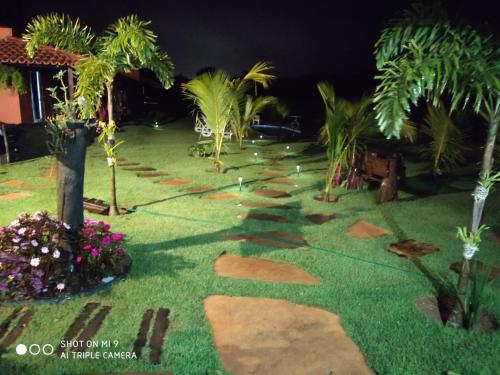 a garden at night with palm trees and lights at Paraíso Capitólio Suítes Pousada in Capitólio