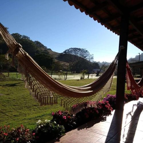 a hammock in a field of grass with flowers at Paraíso Capitólio Suítes Pousada in Capitólio