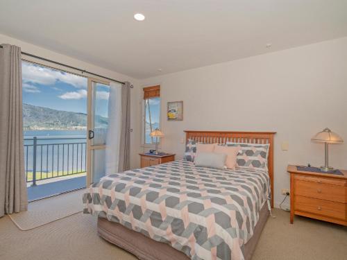 een slaapkamer met een bed en een groot raam bij Tairua Waterfront Retreat - Tairua Apartment in Tairua