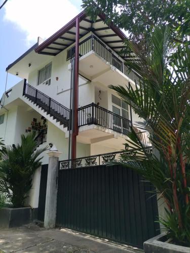 una casa blanca con una valla negra en Ceylon Ramble Villa, en Hikkaduwa