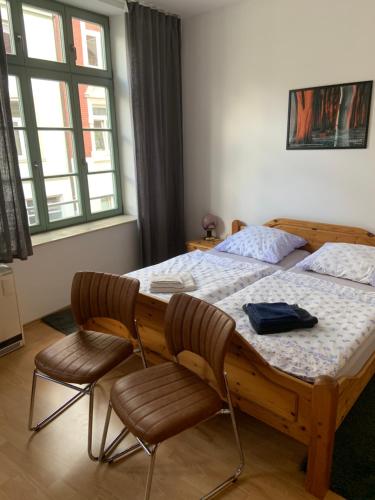 a bedroom with a wooden bed and two chairs at Altstadt Ferienwohnung in Wismar