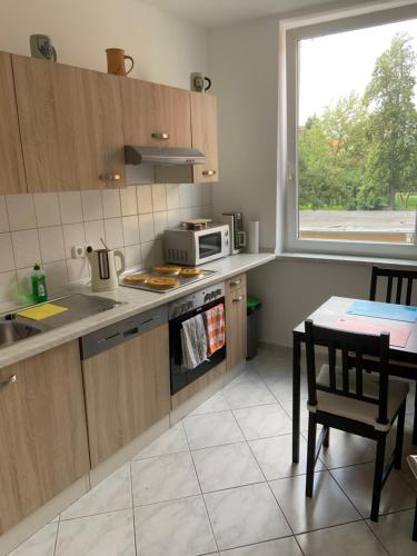 eine Küche mit einer Mikrowelle, einem Tisch und einem Fenster in der Unterkunft Altstadt Ferienwohnung in Wismar