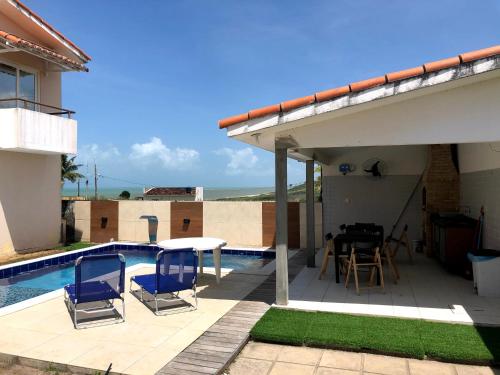 d'une terrasse avec des chaises et une table à côté de la piscine. dans l'établissement Casa completa com piscina e área de laser completa na praia BELA - PB, à Pitimbu