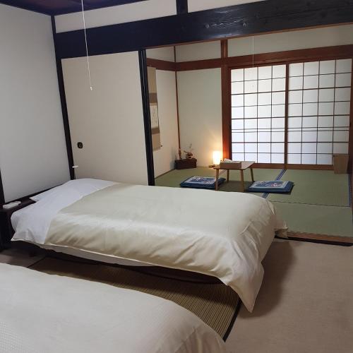 a bedroom with two beds and two windows at 旅籠まさら HATAGO MaSaRa in Chikatsuyu