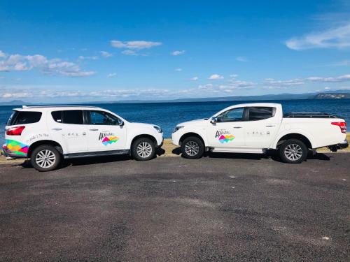 two white trucks parked next to the ocean at Tongariro Adventures The Lodge in Kuratau