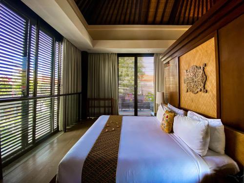 a bedroom with a large bed in a room with windows at Puri Hiromi Boutique Residence in Sanur