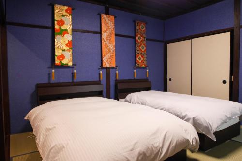 2 Betten in einem Zimmer mit blauen Wänden und Fenstern in der Unterkunft Kanazawa Machiya Aburaya in Kanazawa