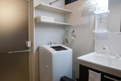 ein kleines Bad mit einer Waschmaschine und einem Waschbecken in der Unterkunft Kanazawa Machiya Aburaya in Kanazawa