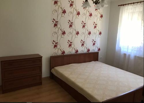 een slaapkamer met een bed en bloemrijk behang bij Panoráma Apartman Ház in Pannonhalma