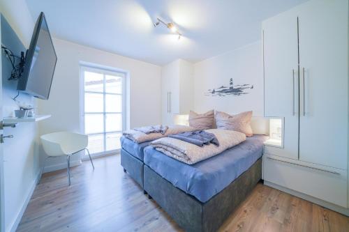 ein Schlafzimmer mit einem Bett in einem Zimmer mit weißen Wänden in der Unterkunft Südstrandhus Urlaub mit Hund Wohnung 2 unten in Borkum