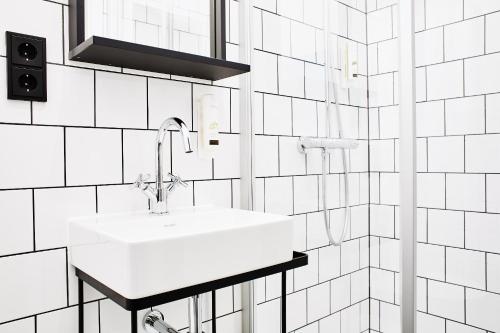 een witte wastafel in een badkamer met witte tegels bij Winterfeld Guest House Bodenmais in Bodenmais