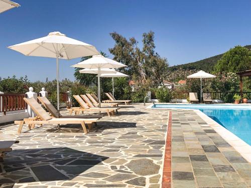 a swimming pool with chairs and umbrellas next to a swimming pool at Pleiades Samos in Marathokampos