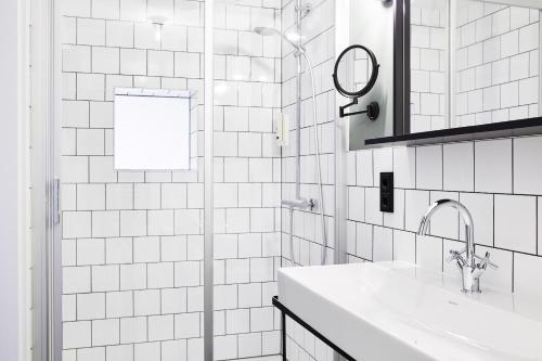 a white tiled bathroom with a sink and a mirror at Winterfeld Guest House Bodenmais in Bodenmais
