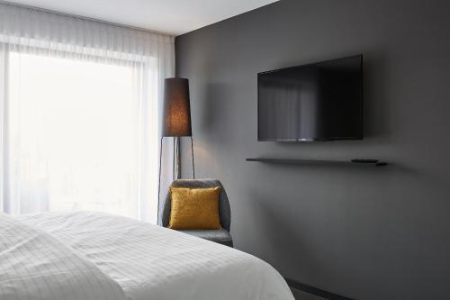 a bedroom with a bed and a tv and a chair at Winterfeld Guest House Bodenmais in Bodenmais