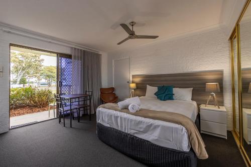 a bedroom with a large bed and a balcony at Bribie Waterways Motel in Bongaree