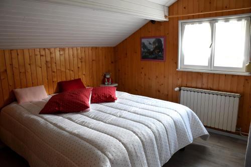 a bedroom with a large bed with red pillows at Gîte 60M2 in Xonrupt-Longemer