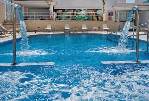 een groot zwembad met fonteinen in een gebouw bij Hotel Biniamar in Cala Millor