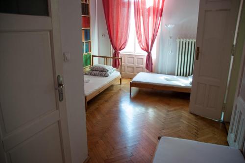 a room with two beds and a window with red curtains at Trzy Kafki Private Rooms in Krakow