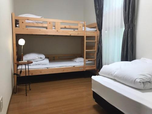 Hotel Daisen Shirogane في Daisen: سريرين بطابقين في غرفة مع طاولة ومصباح