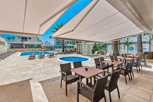 un patio con mesas y sillas y una piscina en Hotel Biniamar en Cala Millor