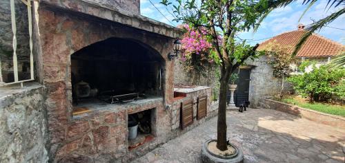an outdoor brick oven with a tree in a courtyard at Villa Stella Rose in Lustica