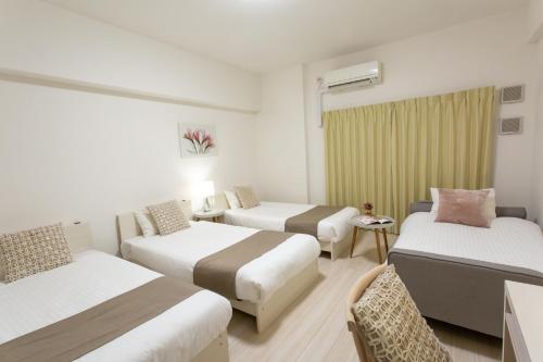 Una habitación de hotel con tres camas y una ventana. en Nedoco Osaka West, en Osaka