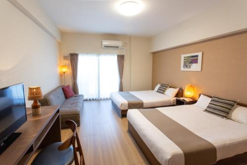 a hotel room with two beds and a flat screen tv at Nedoco Osaka West in Osaka