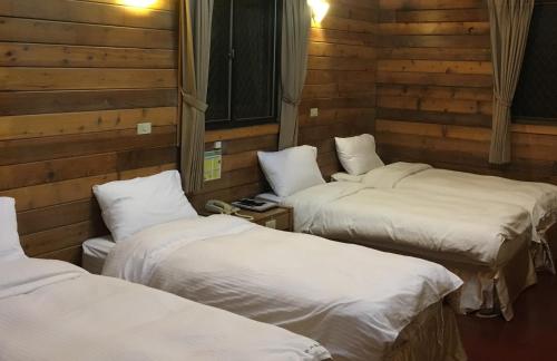 three beds in a room with wooden walls at Sun Moon Lake Youth Hostel in Yuchi
