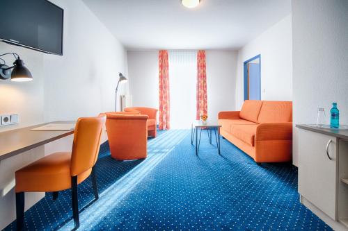 a living room with orange chairs and a table at ACHAT Hotel Zwickau in Zwickau